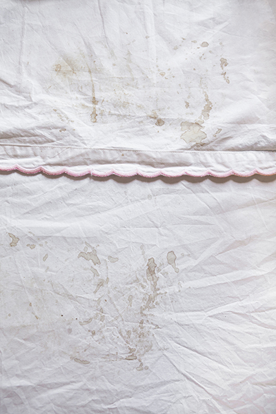 20" x 30" Archival inkjet print. Color photograph. White sheets, pink scallop trim, dirty stains, wrinkled.