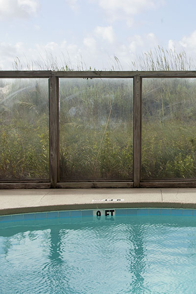 20" x 30" archival inkjet print color photograph. Blue pool, green grass, wooden fence, glass baricade, 9 foot deep end, beach