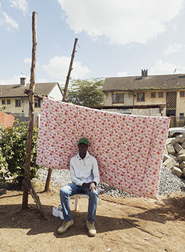 Portrait of a man in a green hat in front of gravel and flowered blanket background
