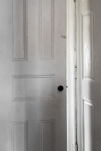 20" x 30" Archivla Inkjet Print. Corner of two white doors, one ajar. Light spilling in. Color Photograph.